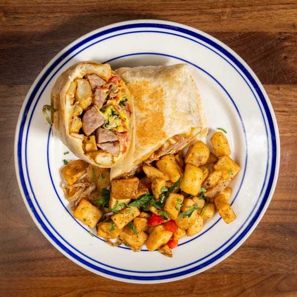 Breakfast burrito with sausage, eggs, and potatoes, served with a side of home fries.