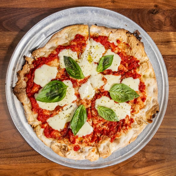 A freshly baked Margherita pizza with melted mozzarella, red sauce, basil, and olive oil.