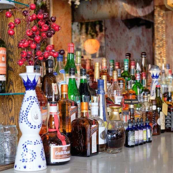 A bar counter filled with various liquor bottles, including Grand Marnier and Cointreau, and a decorative vase.
